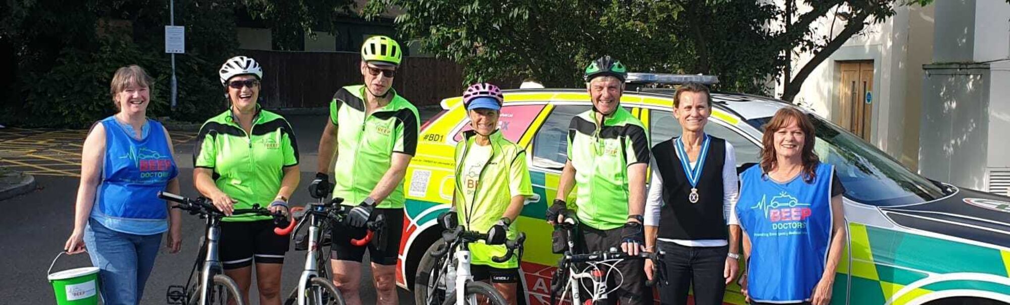BEEP doctors and their bikes stood lined up in front of their BEEP car whilst taking part in the 2024 cycle challenge
